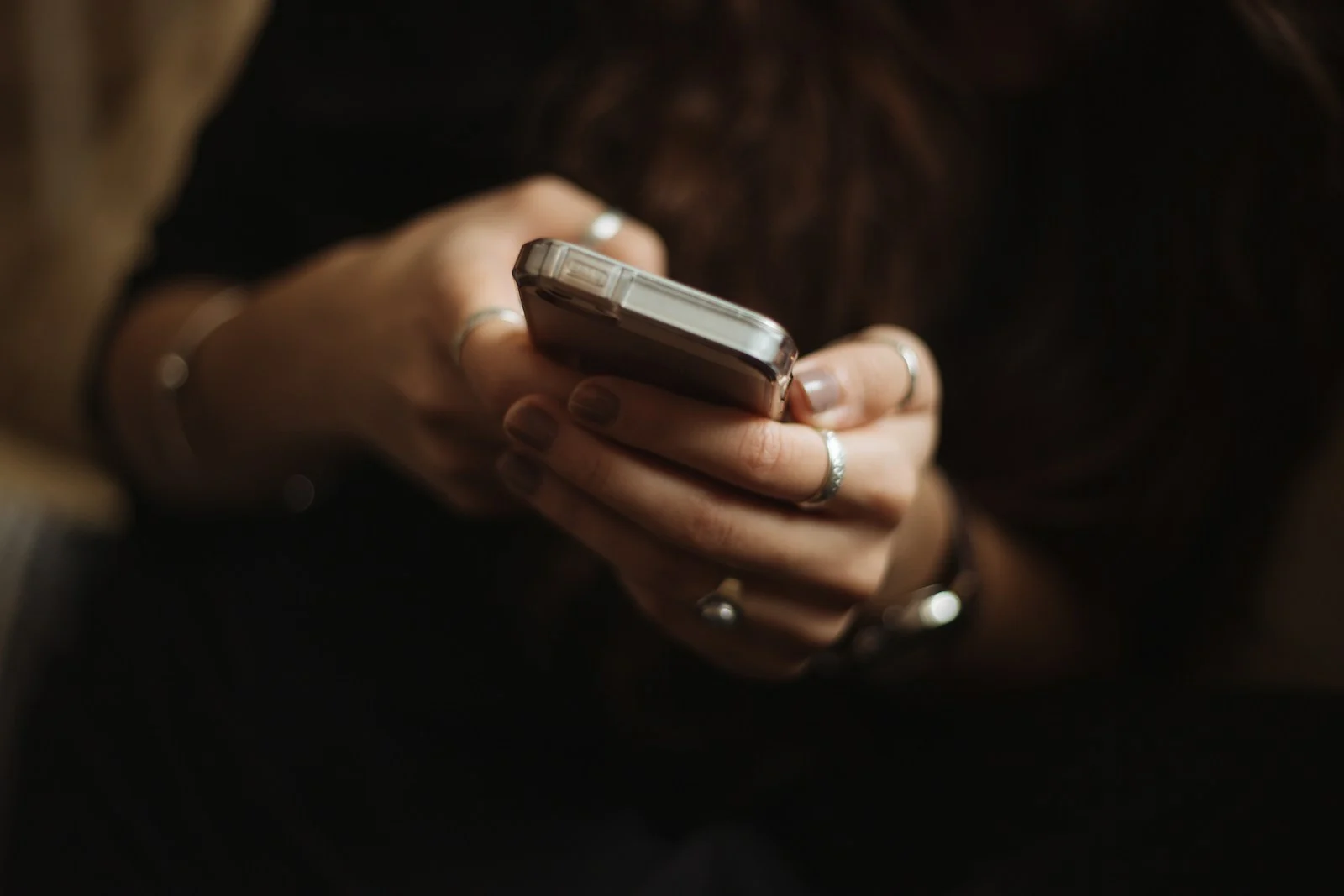 Close-up of hands holding and using a smartphone against a softly blurred background.